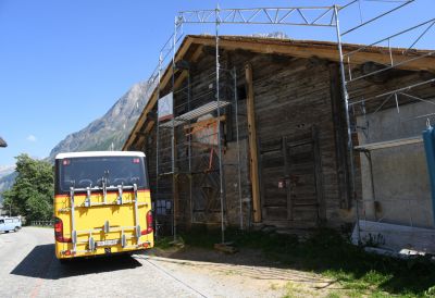 Postauto vor dem Walserama in Nufenen, das momentan ein neues Dach erhaelt.jpg